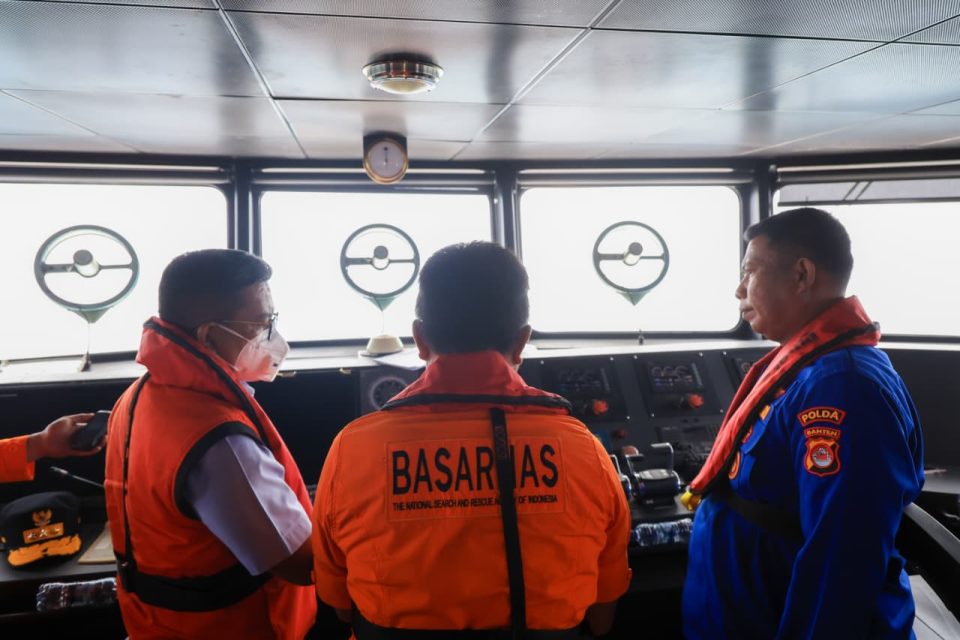 Gubernur Banten Andra Soni menggunakan pelampung jingga sedang berdiskusi dengan petugas Basarnas dan anggota Polda Banten di dalam ruang kemudi kapal penyelamat saat operasi SAR di perairan Selat Sunda.