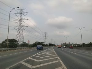 Marka jalan tol bercabang dengan latar belakang menara transmisi listrik SUTET